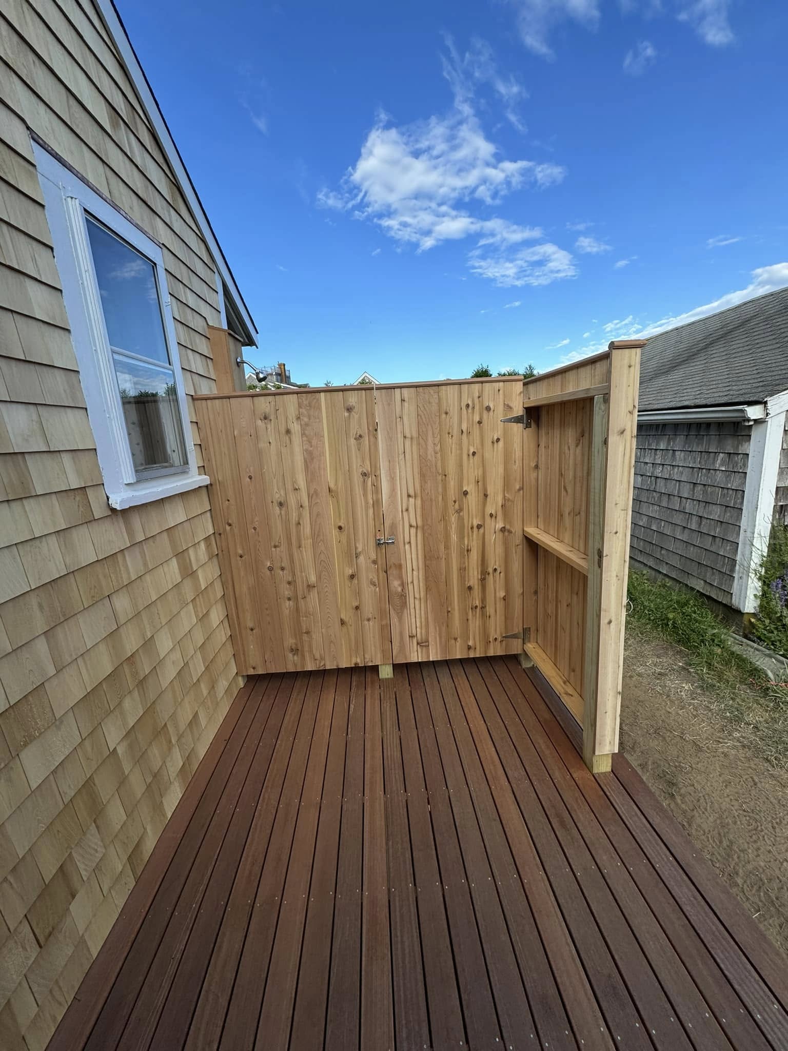 Wide view of outdoor shower with deck and Nantucket shingles